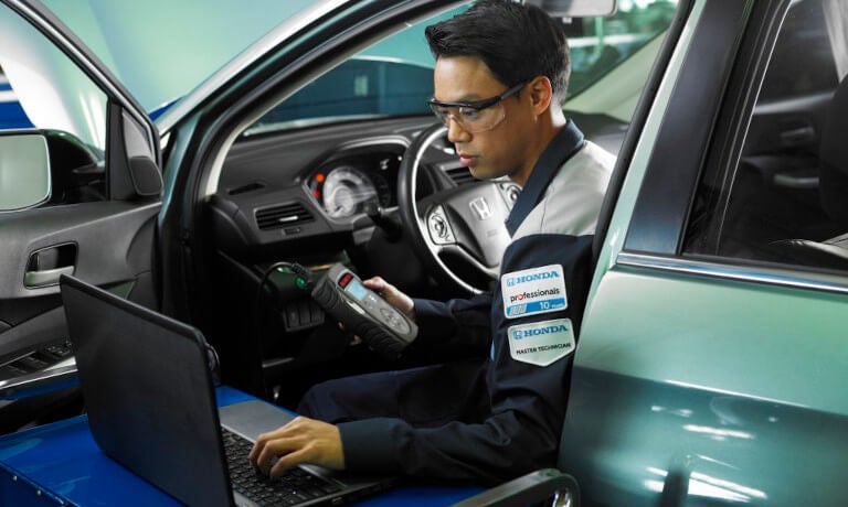 Honda technician in driver's seat with laptop